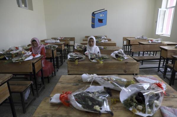 Schoolgirls sit inside a classroom with bouquets of flowers on empty desks as a tribute to those killed in the brutal May 8 bombing of the Syed Al-Shahda girls school, in Kabul, Afghanistan, Sunday, May 16, 2021. On Sunday parents of scores of young girls killed in the bombing demonstrated in the mostly Shiite neighborhood of Dasht-e-Barchi to demand the government provide them with greater security. They said 90 people were killed. (AP Photo/Rahmat Gul)