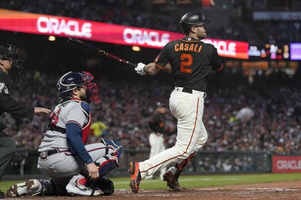 San Francisco Giants' Curt Casali (2) hits a two-run single in front of Atlanta Braves catcher Travis d'Arnaud during the fourth inning of a baseball game in San Francisco, Saturday, Sept. 18, 2021. (AP Photo/Jeff Chiu)
