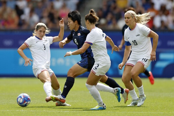 Japan's Kiko Seike is challenged by Korbin Albert, left, Emily Fox and Lindsey Horan, right, of the United States during the quarterfinal women's soccer match between the United States and the Japan at the Parc des Princes at the 2024 Summer Olympics, Saturday, Aug. 3, 2024, in Paris, France. (AP Photo/Aurelien Morissard)