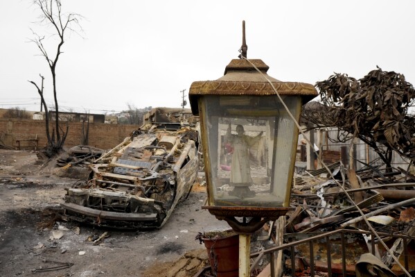 A glass niche holds a statue of Pope John Paul II amid the charred debris left by a forest fire that reached Vina del Mar, Chile, Tuesday, Feb. 6, 2024. (AP Photo/Esteban Felix)