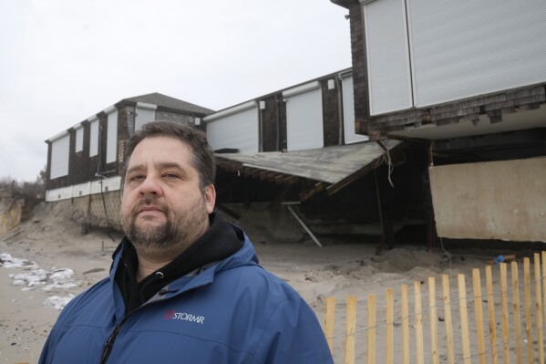 Conrad Ferla, founder of Protecting Coastal Access, stands for a photograph in front of a damaged structure on Dunes Club Beach, Thursday, Jan. 25, 2024, in Narragansett, R.I. Experts say erosion and receding shorelines are becoming more common due to ocean rise and climate change. (AP Photo/Steven Senne)