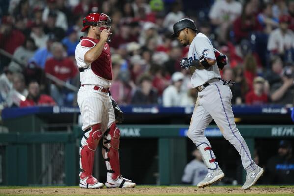 Miami Marlins' Luis Arraez scores past Philadelphia Phillies' J.T. Realmuto after hitting a home run off of Philadelphia Phillies' Connor Brogdon during the seventh inning of a baseball game, Tuesday, April 11, 2023, in Philadelphia. (AP Photo/Matt Rourke)