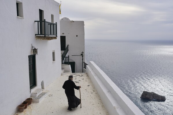 O monge cristão ortodoxo Padre Spyridon caminha no Mosteiro de Panagia Hozoviotissa enquanto o Mar Egeu é visto à direita, na ilha de Amorgos, Grécia, na quarta-feira, 27 de março de 2025. (Foto AP/Petros Giannakouris)