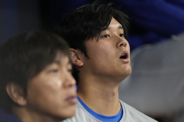 Los Angeles Dodgers designated hitter Shohei Ohtani (right) and translator Ippei Mizuhara sit in the dugout during the baseball season opener against the San Diego Padres at Gocheok Sky Dome in Seoul, South Korea on Wednesday, March 20, 2024. player. A Japanese baseball star was accused of illegal gambling and theft, and his best friend was fired from the Dodgers.  (AP Photo/Lee ​​Jin Man)