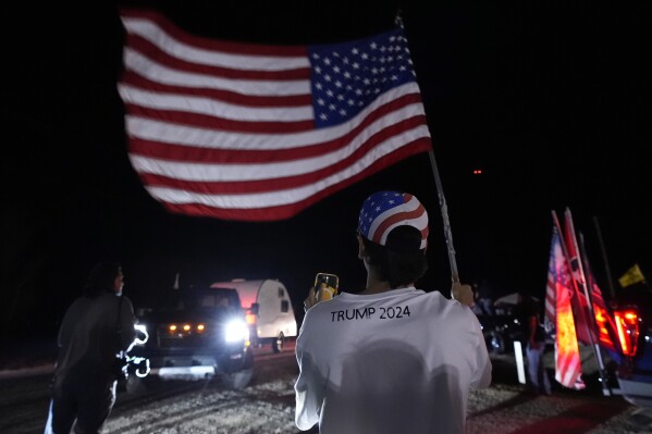 A man waves a flag as a "Take Our Border Back" convoy arrives in Quemado, Texas, Friday, Feb. 2, 2024. The group will hold a rally the following day. (AP Photo/Eric Gay)