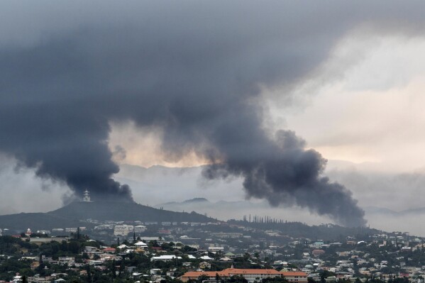 Smoke rises during protests in Noumea, New Caledonia, Wednesday May 15, 2024. France has imposed a state of emergency in the French Pacific territory of New Caledonia. The measures imposed on Wednesday for at least 12 days boost security forces' powers to quell deadly unrest that has left four people dead, erupting after protests over voting reforms. (AP Photo/Nicolas Job)
