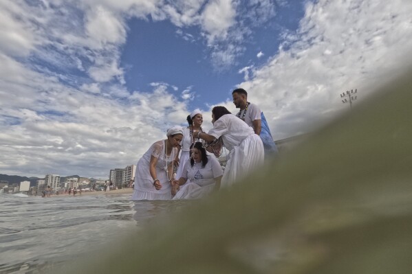 Devotees pray in Arpoador Beach during an annual celebration honoring Yemanja, the African goddess of the sea, in Rio de Janeiro, Sunday, Feb. 2, 2025. (AP Photo/Bruna Prado)