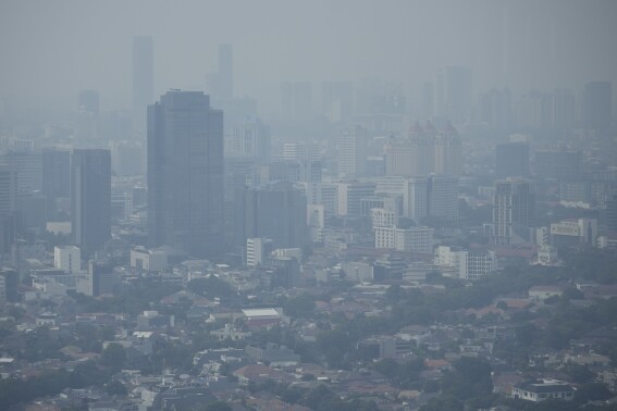 FILE - Haze blankets the main business district in Jakarta, Indonesia, Aug. 11, 2023. The world’s corporations produce so much climate change pollution, it could eat up about 44% of their profits if they had to pay damages for what they spew, according to a study on Thursday, Aug. 24, by economists of nearly 15,000 public companies. (AP Photo/Dita Alangkara, File)