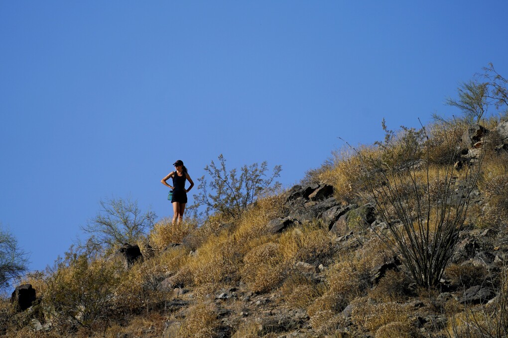 A hiker pauses during her hike early Monday, July 10, 2023, in Phoenix. National Weather Service says Phoenix has had 10 consecutive days of 110 degrees or above. (AP Photo/Matt York)