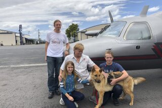 
              In this photo provided by the Humane Society of Broward County, kneeling from left to right, Chloe, Doug and Chase Peterson greet their long-lost German Shepherd dog Cedar on Saturday, April 20, 2019, at Fort Lauderdale Executive Airport, in Fort Lauderdale, Fla. Cedar, 2, was stolen from her home in Southwest Ranches in 2017 and located this month in Colorado. Standing is pilot Ted DuPuis. (Cherie Wachter/Humane Society of Broward County via AP)
            