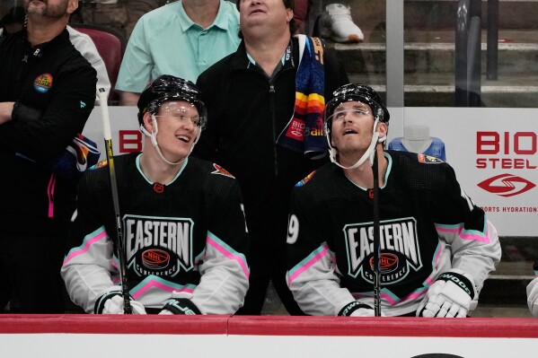 Atlantic Division's Brady Tkachuk, of the Ottawa Senators (7) and Matthew Tkachuk, of the Florida Panthers (19) watch the rerun of a goal by Matthew assisted by Brady during the NHL All Star hockey game, Feb. 4, 2023, in Sunrise, Fla. (AP Photo/Marta Lavandier, File)