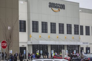 FILE - In this March 30, 2020 file photo, workers at Amazon's fulfillment center in Staten Island, N.Y., gather outside to protest work conditions in the company's warehouse in New York. Amazon fired a worker who staged the walkout to demand greater protection against the new coronavirus, saying the employee himself flaunted distancing rules and put others at risk. The decision prompted a rebuke from New York Attorney General Letitia James, who called on the National Labor Relations Board to investigate. (AP Photo/Bebeto Matthews, File )