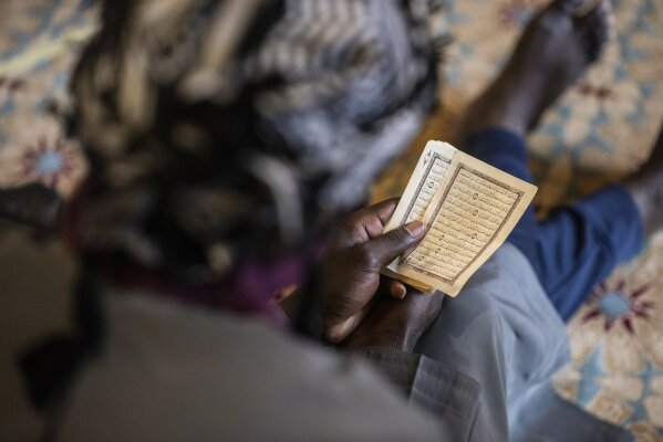 In this photo taken Friday, May 15, 2020, a follower of the Senegalese Mouride brotherhood, an order of Sufi Islam, reads the Quran during Muslim Friday prayers at West Africa's largest mosque the Massalikul Jinaan, in Dakar, Senegal. A growing number of mosques are reopening across West Africa even as confirmed coronavirus cases soar, as governments find it increasingly difficult to keep them closed during the holy month of Ramadan. (AP Photo/Sylvain Cherkaoui)