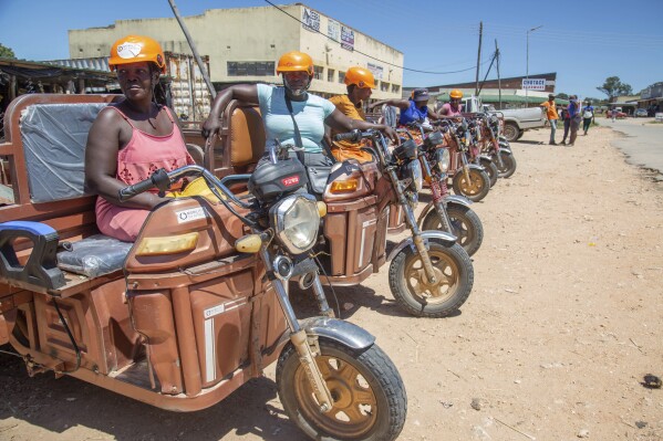 Women sit on their three wheeler tri-cycles waiting for clients at a market place in Hwedza, Zimbabwe, Thursday, March 6, 2025. (AP Photo/Aaron Ufumeli)