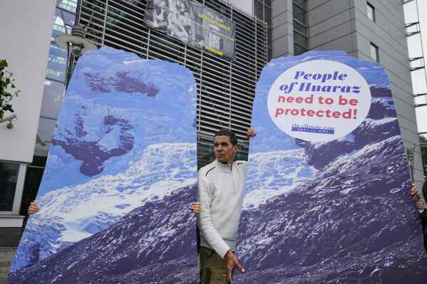 A protestor demands climate justice in front of the Higher Regional Court in Hamm, Germany, ahead of the verdict in the climate lawsuit brought by Peruvian farmer Luciano Lliuya against German energy company RWE, Wednesday, May 28, 2025. (AP Photo/Martin Meissner)