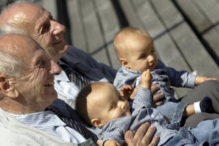 FILE - In this Saturday, June 18, 2005 file photo, identical twins Alf, left, and Sven Fehnhanhn, left background, 79, from Kassel, pose along with seven-month-old Luis Carl, right, und Albert Frank Millgramm, right background, during a twins' meeting in Berlin. According to research published on Thursday, Jan. 7, 2021, identical twins are not exactly genetically the same. (AP Photo/Jockel Finck)