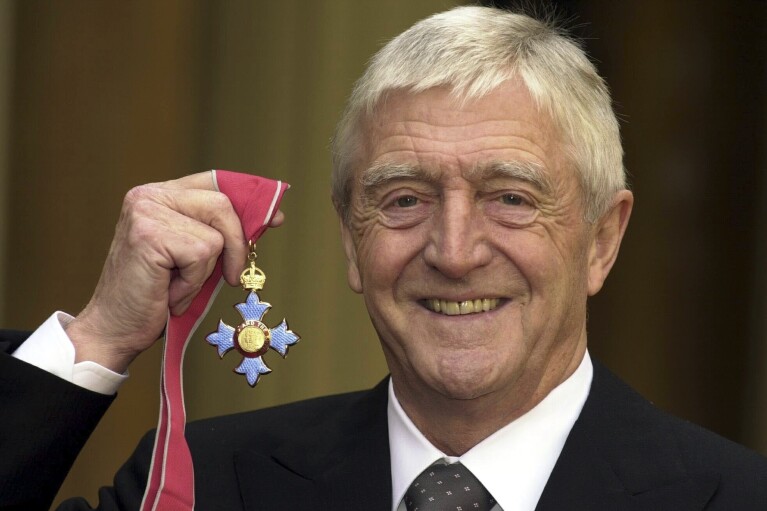 FILE - Michael Parkinson poses for the media after being awarded a CBE at Buckingham Palace in London, Nov. 24, 2000. Michael Parkinson, the renowned British broadcaster who interviewed everyone from Muhammed Ali, David Bowie and Miss Piggy, has died. He was 88. In a statement Thursday, Aug. 17, 2023 to the BBC, his family said Parkinson died “peacefully at home last night in the company of his family." (Kirsty Wigglesworth/Pool Photo via AP, file)