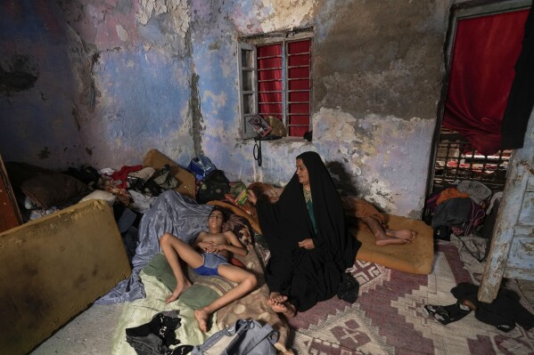 A Iraqi woman fans her child during a power outage at their home in Baghdad, Iraq, Thursday, July, 6, 2023. (AP Photo/Hadi Mizban)