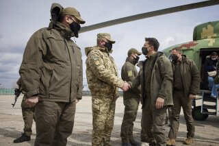 Ukrainian President Volodymyr Zelenskiy shakes hands a soldier as he visits the war-hit Donbas region, eastern Ukraine, Thursday, April 8, 2021. Ukraine is at the center of a major geopolitical battle in the eastern part of the country with Moscow backed separatists. (Ukrainian Presidential Press Office via AP)