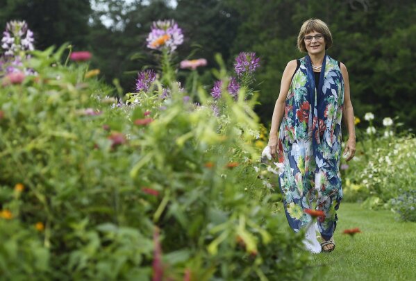In this Thursday August 8, 2019 photo, Karen Breda poses for a photograph in a garden in West Hartford, Conn. Breda attended Woodstock to see a music concert that included the Who, Jimi Hendrix, Jefferson Airplane and Crosby, Stills, Nash & Young in the lineup.  (AP Photo/Jessica Hill)