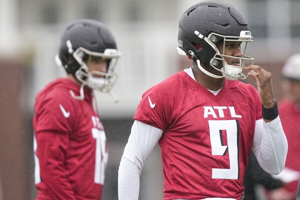 Atlanta Falcons quarterbacks Michael Penix Jr., right, and Kirk Cousins, left, run drills during an NFL football mini training camp practice on Tuesday, May 14, 2024, in Flowery Branch, Ga. (AP Photo/Brynn Anderson)