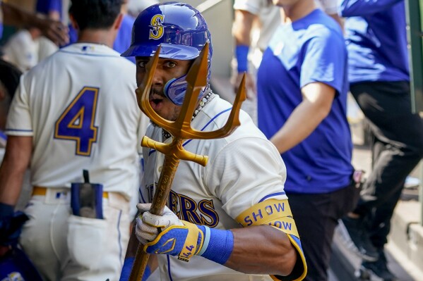 Seattle Mariners' Julio Rodriguez holds a trident in the dugout after hitting a two-run home run to score Josh Rojas against the Kansas City Royals during the fifth inning of a baseball game, Sunday, Aug. 27, 2023, in Seattle. (AP Photo/Lindsey Wasson)