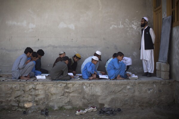 FILE - In this March 19, 2013 file photo, afghan boys study in a makeshift school in the village of Budyali, Nangarhar province, Afghanistan. The Taliban's "abusive" educational policies are harming boys as well as girls in Afghanistan, according to a Human Rights Watch report published Wednesday. (AP Photo/Anja Niedringhaus, File)