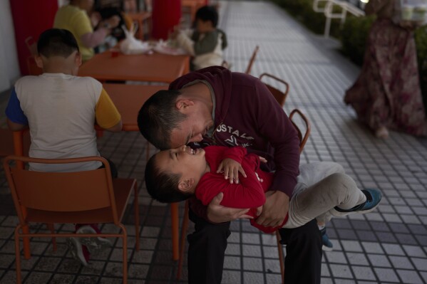 Anton Le, who was 5 years old when he and his family arrived in the U.S. from Vietnam via the Philippines, plays with his son, Kevin, while waiting for his order outside a café in the Little Saigon neighborhood of Westminster, Calif., Monday, April 21, 2025. (AP Photo/Jae C. Hong)