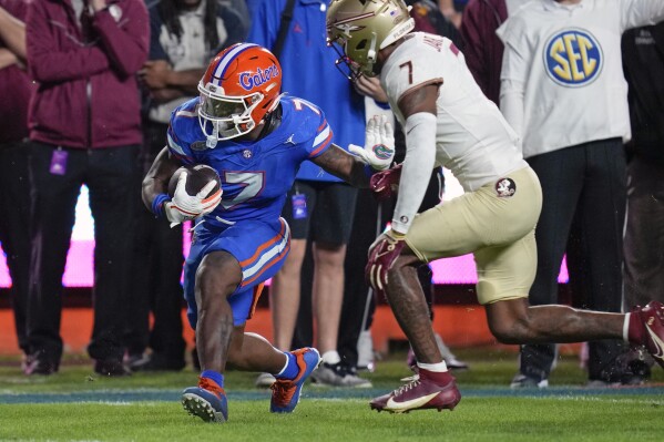 Florida running back Trevor Etienne, left, gains yardage before Florida State defensive back Jarrian Jones, right, can stop him during the first half of an NCAA college football game Saturday, Nov. 25, 2023, in Gainesville, Fla. (APPhoto/John Raoux)
