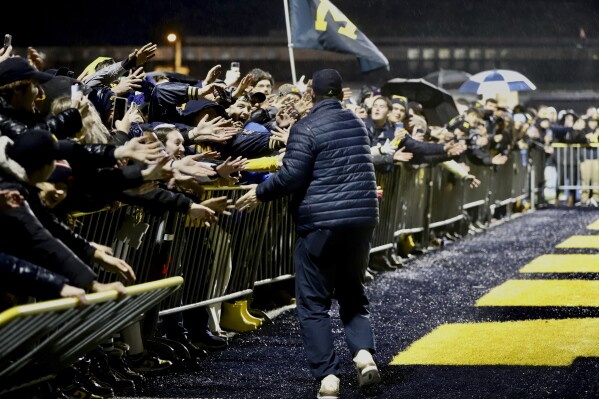 Michigan fans reach over barriers to greet football coach Jim Harbaugh as the Wolverines returned to Ann Arbor, Mich., Tuesday, Jan. 9, 2024, after winning the NCAA College Football Championship title with a win over Washington on Monday night in Houston. (Kimberly P. Mitchell/Detroit Free Press via AP)