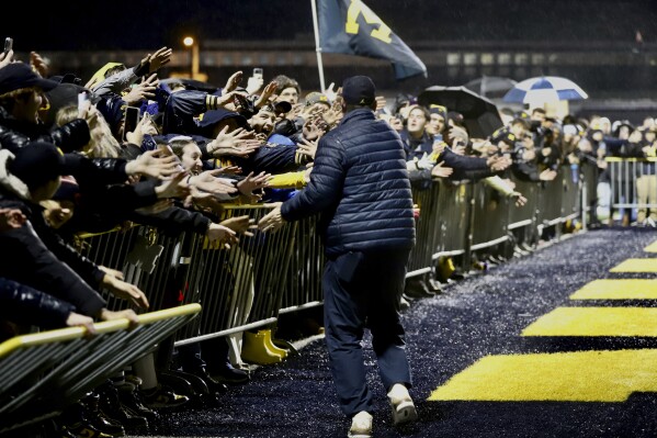 Michigan fans reach over barriers to greet football coach Jim Harbaugh as the Wolverines returned to Ann Arbor, Mich., Tuesday, Jan. 9, 2024, after winning the NCAA College Football Championship title with a win over Washington on Monday night in Houston. (Kimberly P. Mitchell/Detroit Free Press via AP)