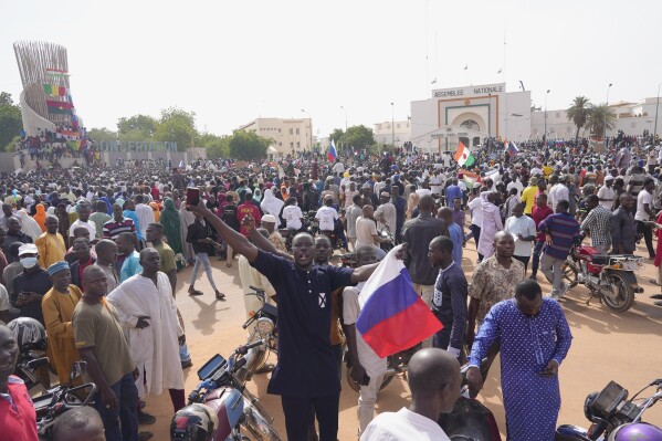 FILE - Nigeriens, some holding Russian flags, participate in a march called by supporters of coup leader Gen. Abdourahmane Tchiani in Niamey, Niger, on July 30, 2023. Three West African nations led by military juntas met this week to strengthen a newly formed alliance described by some analysts on Friday as an attempt to legitimize their military governments amid coup-related sanctions and strained relations with neighbors. In his first foreign trip since the July coup that brought him into power, Niger’s junta leader, Gen. Abdourahmane Tchiani held separate meetings Thursday Nov. 23, 2023 with his Mali and Burkina Faso counterparts. (AP Photo/Sam Mednick, File)