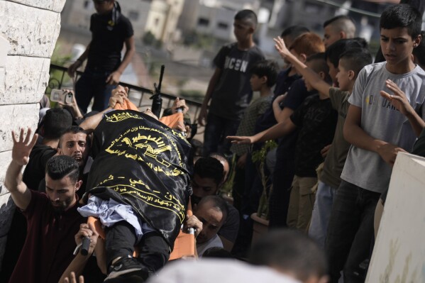 Dolientes cargan el cuerpo de Abdallah Abu Hasan, un militante palestino de 18 años que según las autoridades palestinas fue abatido por fuego israelí, en su funeral en la aldea de Al-Yamoun, cerca de Jenin, Cisjordania, viernes 22 de setiembre de 2023. (AP Foto/Majdi Mohammed)
