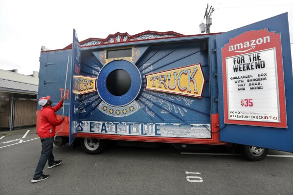 
              In this May 24, 2018, photo Amazon worker Khayyam Kain begins to open an Amazon Treasure Truck at a parking lot in Seattle. The Treasure Truck is a quirky way for the online retailer to connect with shoppers in person, expand its physical presence and promote itself. Amazon has also used the trucks to try to bring people into Whole Foods, the grocery chain it bought last year. The trucks debuted two years ago and now roam nearly dozens of cities in the United States and England. (AP Photo/Elaine Thompson)
            