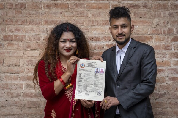 Same-sex couple Surendra Pandey, right, and Maya Gurung, who got married six years ago, pose for a photograph with their marriage certificate during a press meet in Kathmandu, Nepal, Friday, Dec. 1, 2023. The gay couple in Nepal on Wednesday , Nov. 29, became the first in the nation to receive official same-sex marriage status. (AP Photo/Niranjan Shrestha)