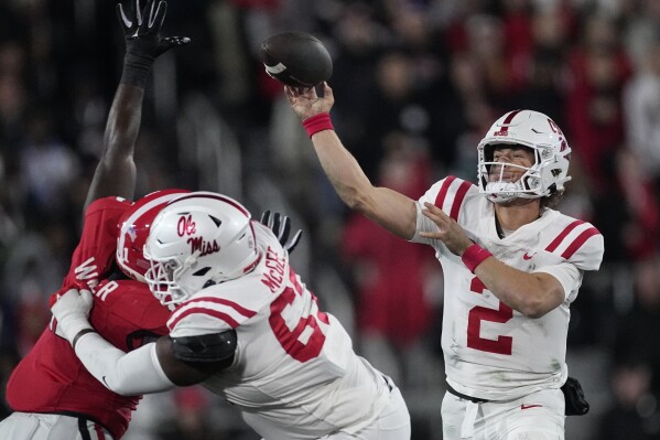 Mississippi quarterback Jaxson Dart (2) throws as offensive lineman Quincy McGee (67) blocks Georgia defensive lineman Tramel Walthour (90) during the first half of an NCAA college football game, Saturday, Nov. 11, 2023, in Athens, Ga. (AP Photo/John Bazemore)