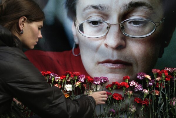 FILE- In this Oct. 7, 2009 file photo, a woman places flowers before a portrait of slain Russian journalist Anna Politkovskaya, in Moscow. A lawyer for a man convicted in the 2006 killing of Russian investigative journalist Anna Politkovskaya received a presidential pardon after a stint fighting in Ukraine. Sergei Khadzhikurbanov was sentenced to 20 years in prison in 2014 for his role in the death of Politkovskaya, who wrote stories critical of Kremlin policies during the early years of President Vladimir Putin’s term, the war in Chechnya and human rights abuses. (AP Photo/Pavel Golovkin, File)