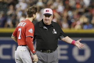 
              FILE - In this May 13, 2018, file photo, MLB umpire Joe West, right, talks with a player in the ninth inning during a baseball game between the Arizona Diamondbacks and the Washington Nationals in Phoenix. West, who has umpired more than 5,000 big league games, said the 2016 TrackMan computer system test was far from perfect. (AP Photo/Rick Scuteri, File)
            