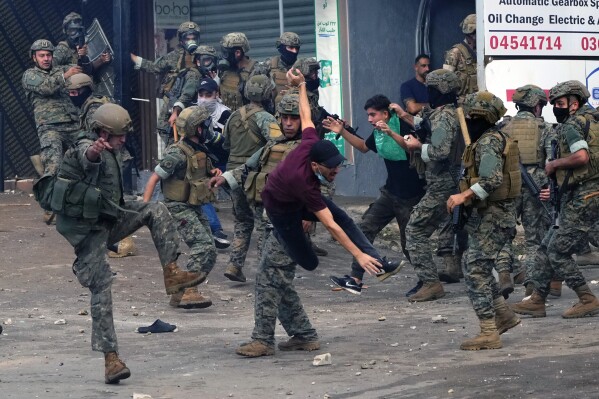 Lebanese army soldiers scuffle with protesters during a demonstration in solidarity with the Palestinian people in Gaza, near the U.S. embassy in Aukar, a northern suburb of Beirut, Lebanon, Wednesday, Oct. 18, 2023. (AP Photo/Hassan Ammar)