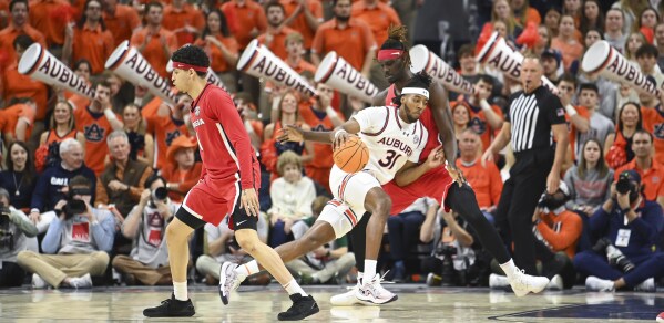 Auburn forward Chaney Johnson (31) drives past Georgia center Somtochukwu Somto Cyril (6) during the first half an NCAA college basketball game Saturday, Feb. 22, 2025, in Auburn, Ala. (AP Photo/Julie Bennett)