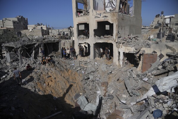 Palestinians look at buildings destroyed in the Israeli bombardment in the morgue in Deir al Balah, Gaza Strip, Tuesday, Nov. 7, 2023. (AP Photo/Hatem Moussa)