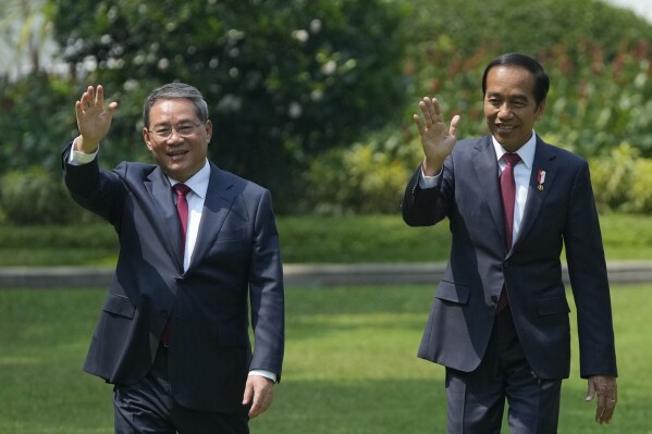 Chinese Premier Li Qiang, left, and Indonesian President Joko Widodo wave at reporters as they walk on the lawn of Merdeka Palace during their meeting in Jakarta, Indonesia, Friday, Sept. 8, 2023. (AP Photo/Achmad Ibrahim)