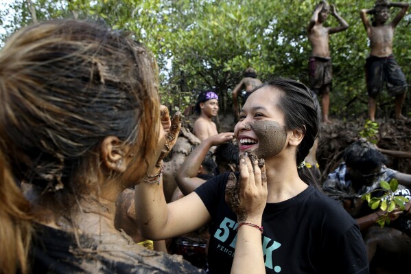 Balinese girls rub mud from a mangrove forest on each other during a mud bath purification ritual as part of Balinese Hindu New Year celebrations at Kedonganan village in Bali, Tuesday, March 12, 2024. (AP Photo/Firdia Lisnawati)