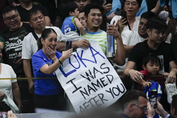 Fans of Slovenia guard Luka Doncic react after he gave his player trophy to them shortly after winning against Italy during the Basketball World Cup classification match in Manila, Philippines, Saturday, Sept. 9, 2023. (AP Photo/Aaron Favila)