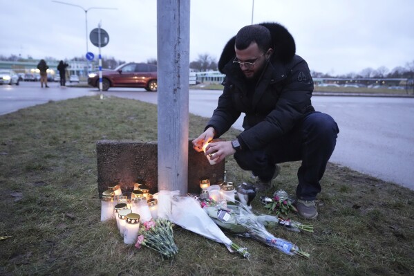 On Wednesday, February 5th, 2025, man lights candles at a makeshift memorial near the scene of a shooting at an adult education centre on the outskirts of Orebro, Sweden (AP Photo/Sergei Grits)