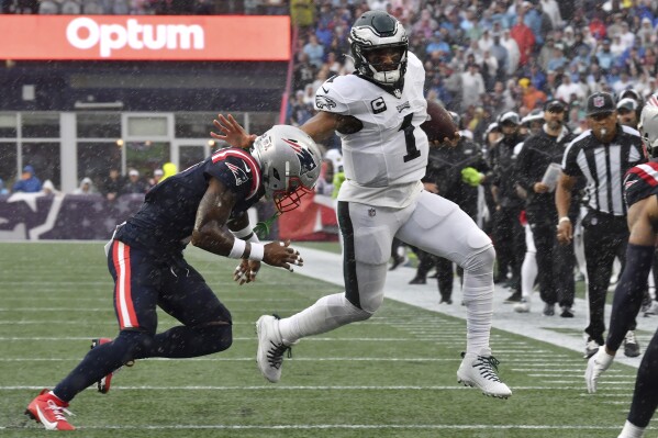 Philadelphia Eagles quarterback Jalen Hurts (1) is pursued by New England Patriots cornerback Jalen Mills, left, in the first half of an NFL football game, Sunday, Sept. 10, 2023, in Foxborough, Mass. (AP Photo/Mark Stockwell)