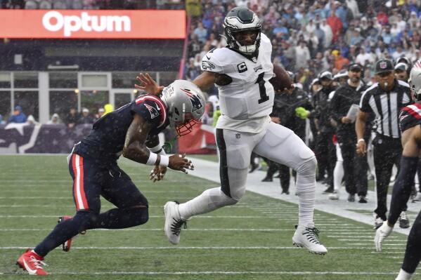 Philadelphia Eagles quarterback Jalen Hurts (1) is pursued by New England Patriots cornerback Jalen Mills, left, in the first half of an NFL football game, Sunday, Sept. 10, 2023, in Foxborough, Mass. (AP Photo/Mark Stockwell)