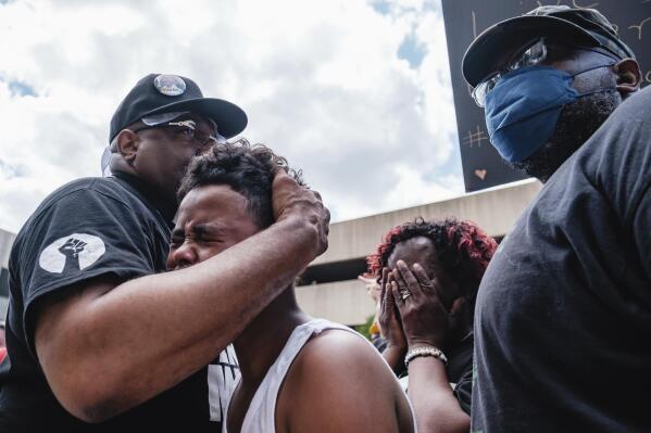 Javon Williams, 13, is comforted by Rev. Jaland Finney, left, as he speaks during a march and rally for Jayland Walker, Sunday, July 3, 2022, in Akron, Ohio. Also pictured at center right is Lanette Williams, reacting after Javon's speech. Williams had just viewed the video released by police detailing the shooting death of Walker. (Andrew Dolph/Times Reporter via AP)