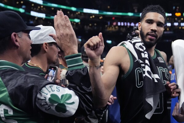 Boston Celtics forward Jayson Tatum, right, gestures to a fan after the Celtics defeated the Cleveland Cavaliers 113-98 in Game 5 of an NBA basketball second-round playoff series Wednesday, May 15, 2024, in Boston. The Celtics advanced to the Eastern Conference finals. (AP Photo/Charles Krupa)