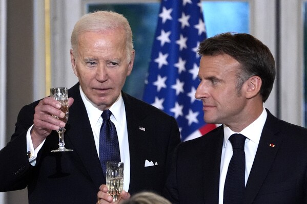 FILE - French President Emmanuel Macron, right, and President Joe Biden toast during a state dinner, June 8, 2024 at the Elysee Palace, in Paris. A Pew survey of democracies around the world finds that views of the U.S. as a model for democracy are slipping and confidence in presumptive Republican presidential nominee Donald Trump is on par with Russian President Vladmir Putin and Chinese President Xi Jinping. (AP Photo/Evan Vucci, File)